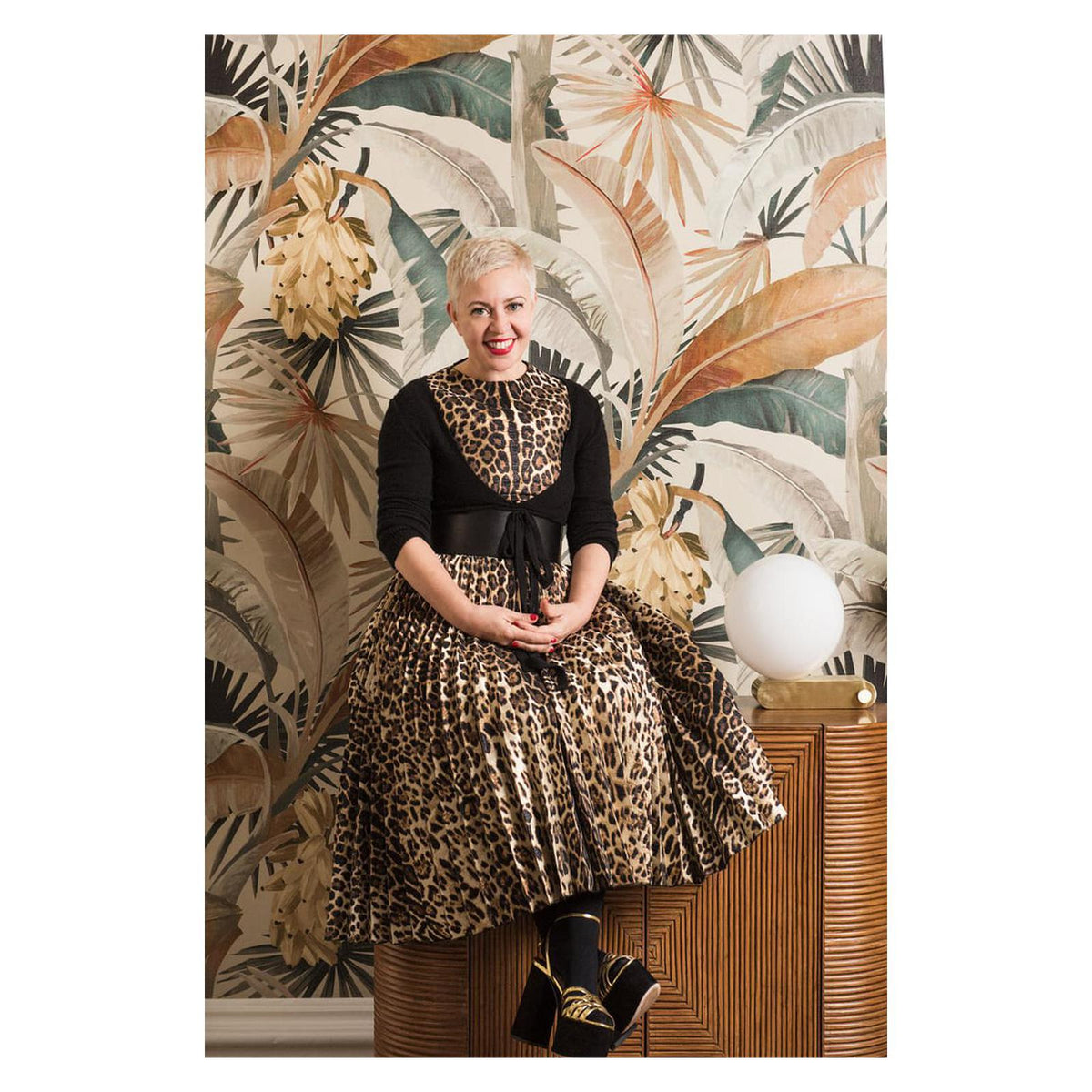 Designer Catherine Martin seated in front of her La Palma wallpaper for Mokum