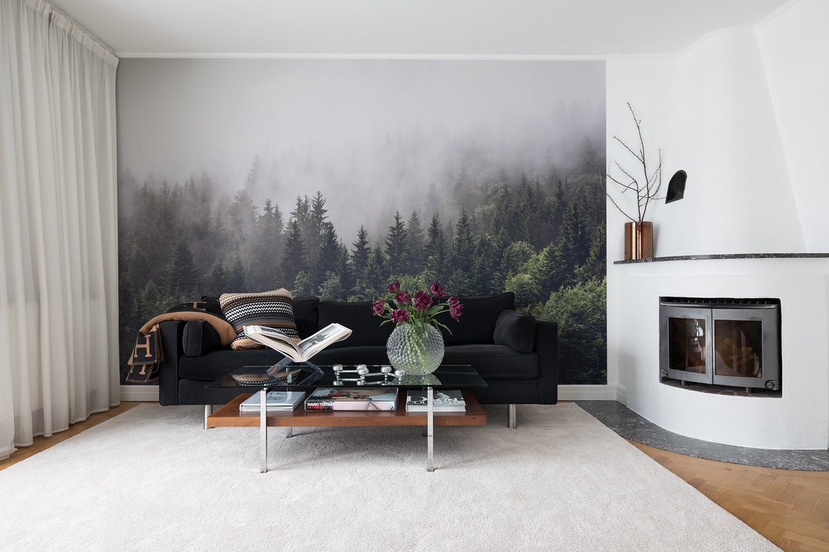 Misty Fir Forest mural by Wallpaper Trader styled in a living room behind a black sofa beside a fireplace