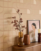 Looping Line wallpaper in peach with copper lines behind vases and artwork on a sideboard