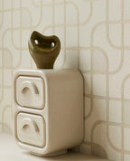 Looping Line wallpaper in green with gold lines, close-up behind a ceramic sculpture