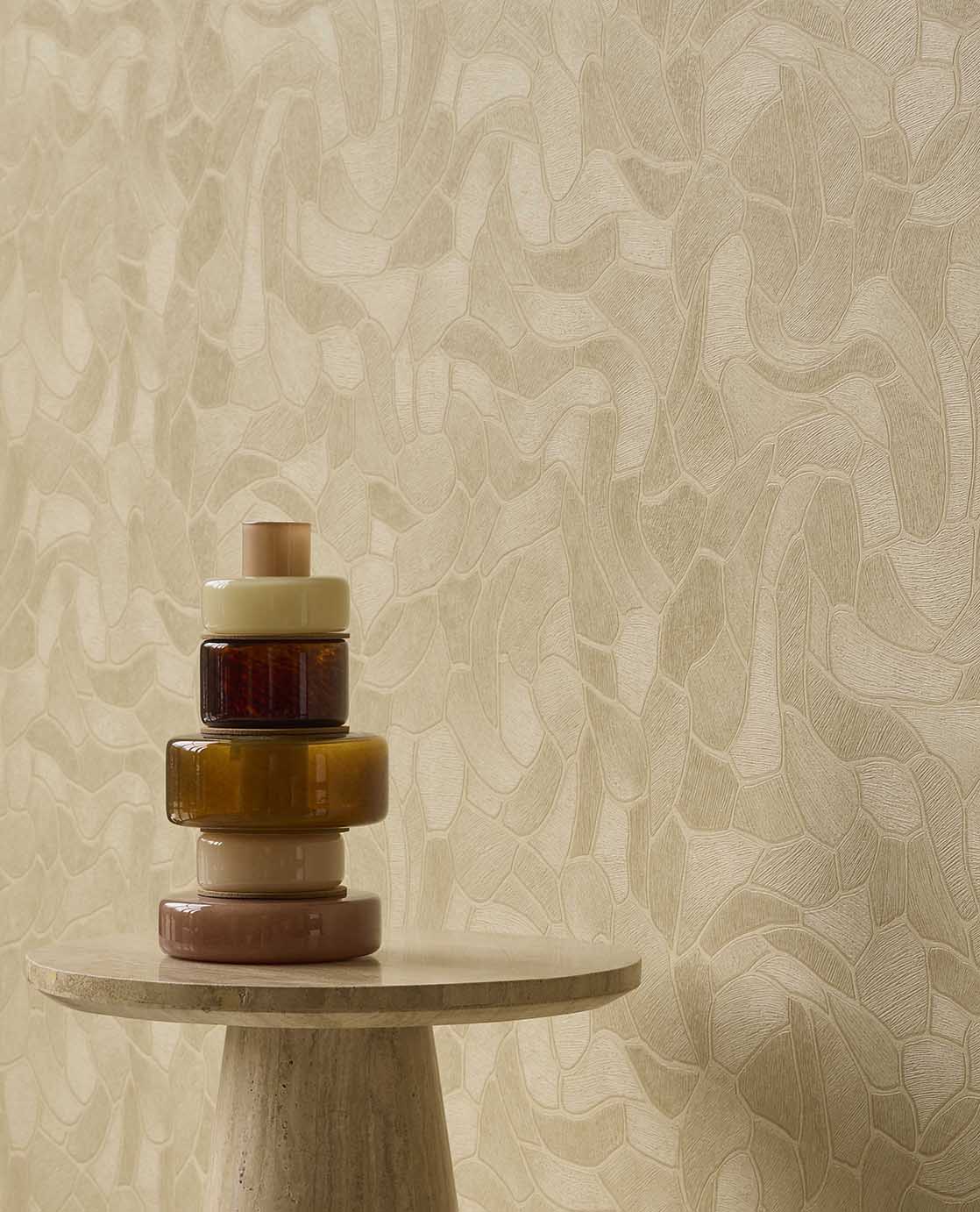Pebble Relief wallpaper in beige behind amber glassware on a stone side table