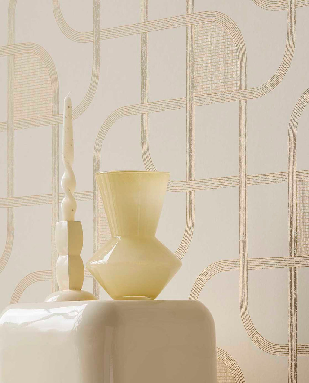 Looping Line wallpaper in cream with gold lines behind a yellow glass vase