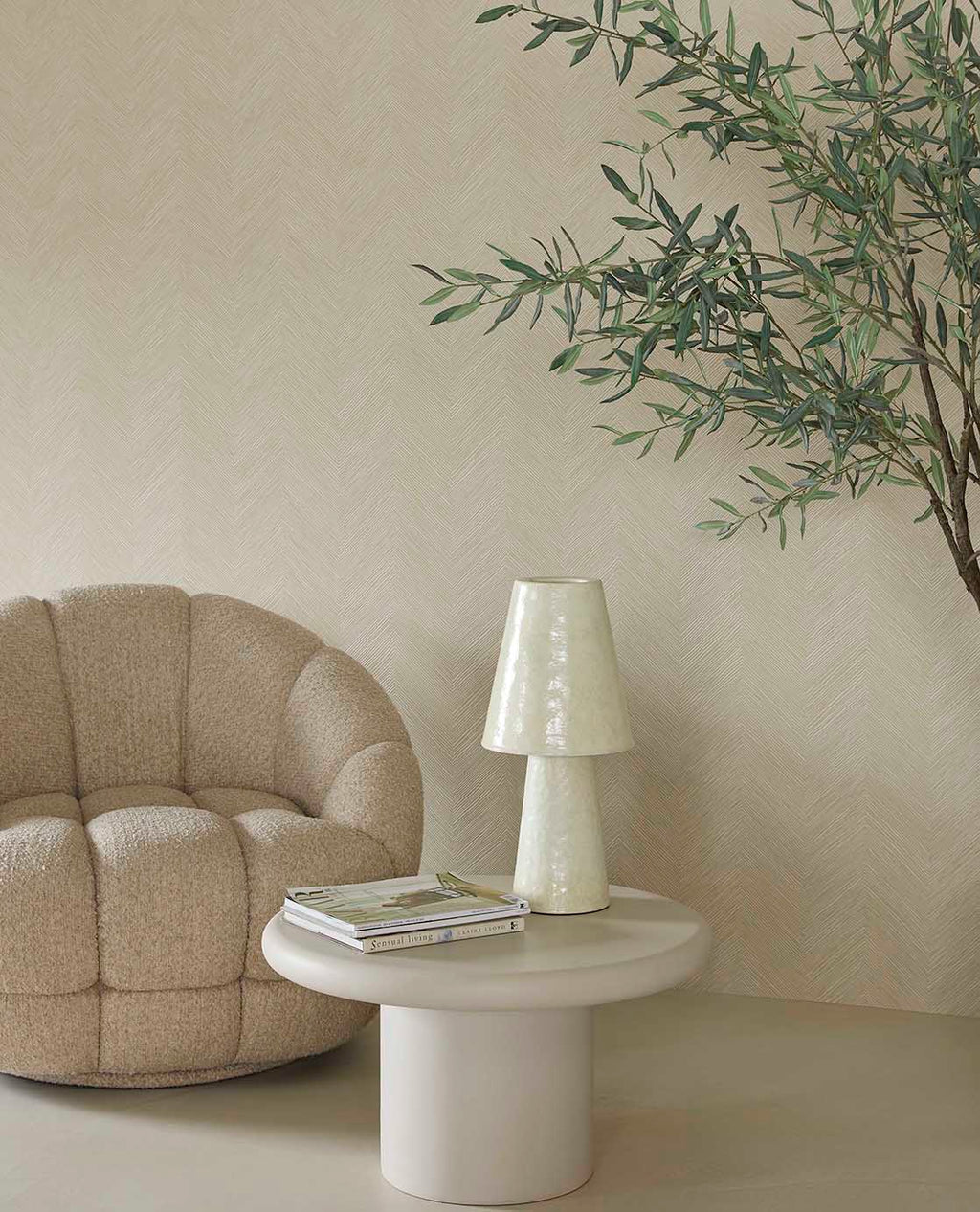 Woven Herringbone wallpaper in beige behind a boucle armchair and side table lamp