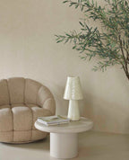 Woven Herringbone wallpaper in beige behind a boucle armchair and side table lamp