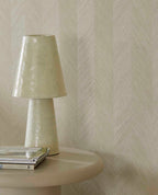 Woven Herringbone wallpaper in beige, close-up behind a ceramic table lamp