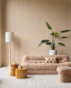 Woven Grid wallpaper in beige in a living room with a velvet sofa, floor lamp and plant