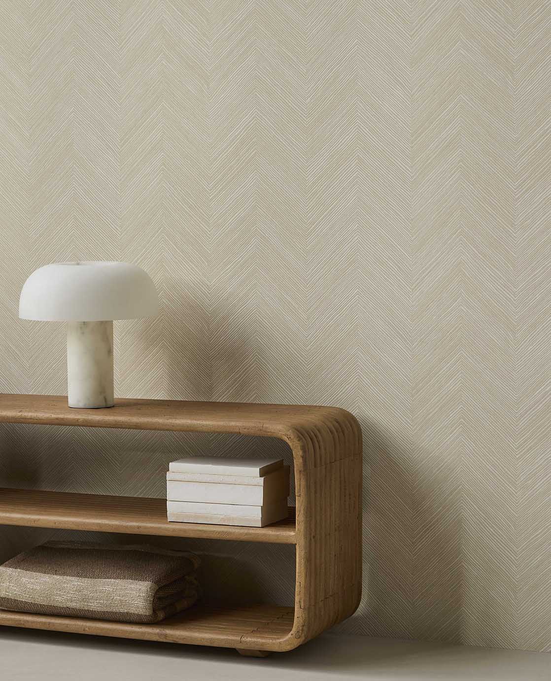 Woven Herringbone wallpaper in pale linen beige behind a curved timber console and lamp