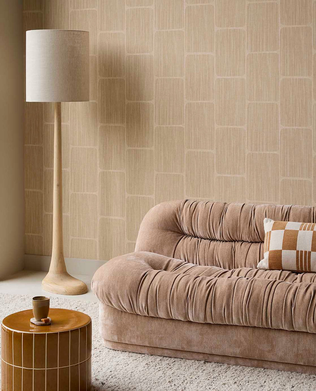 Woven Grid wallpaper in beige behind a velvet sofa and floor lamp