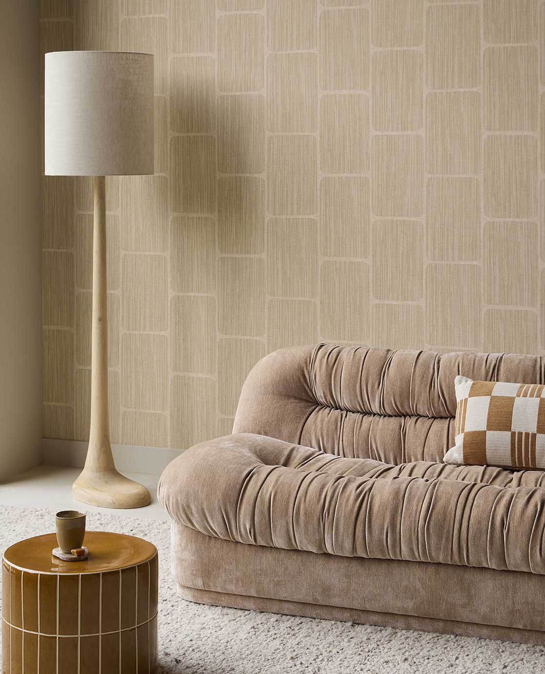 Woven Grid wallpaper in beige behind a velvet sofa and floor lamp