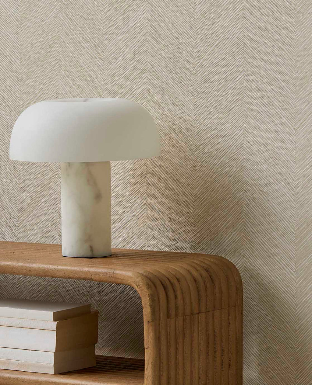 Woven Herringbone wallpaper in pale linen beige, close-up behind a marble lamp