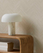 Woven Herringbone wallpaper in pale linen beige, close-up behind a marble lamp