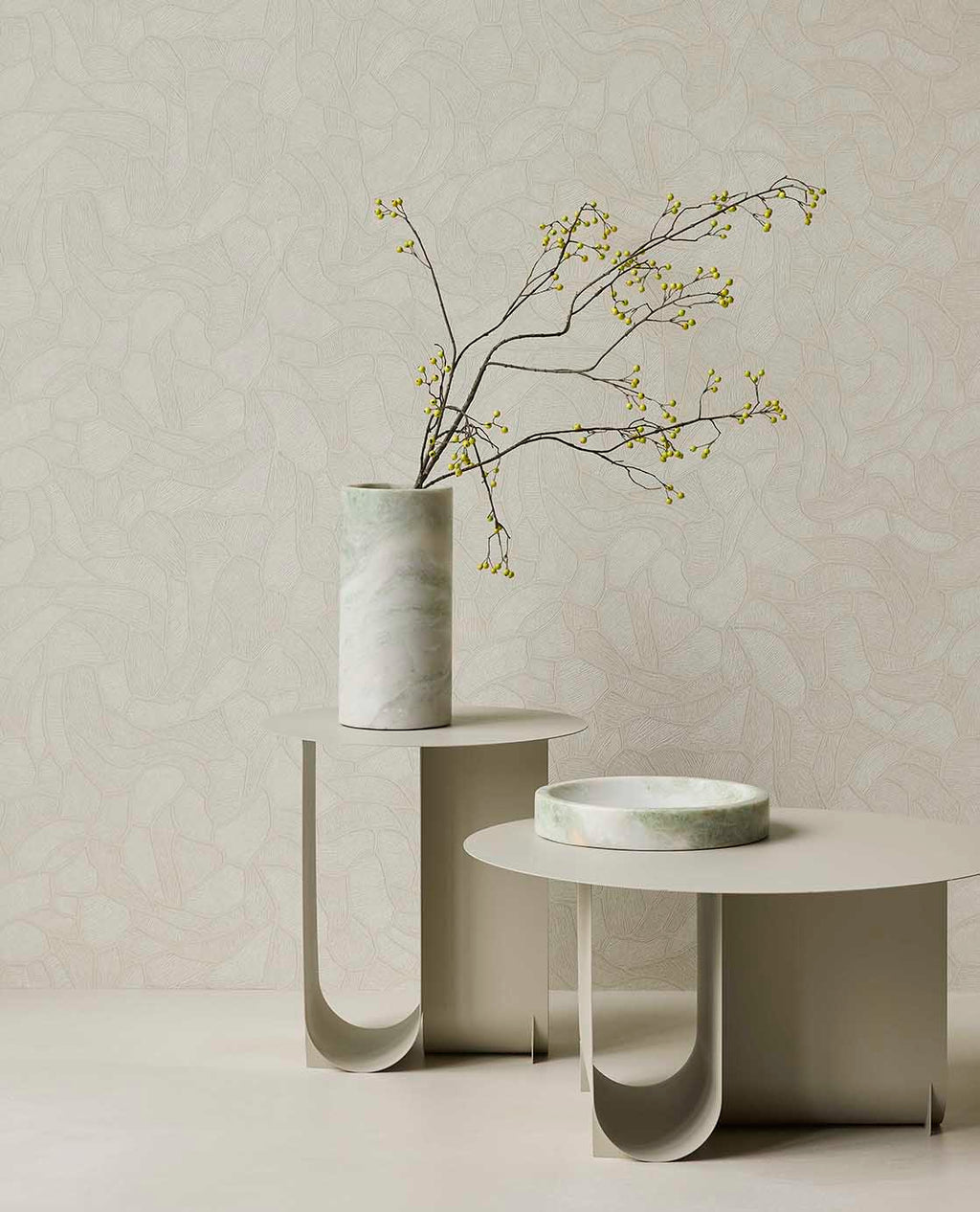 Pebble Relief wallpaper in light green behind white side tables with a vase of branches