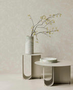 Pebble Relief wallpaper in light green behind white side tables with a vase of branches