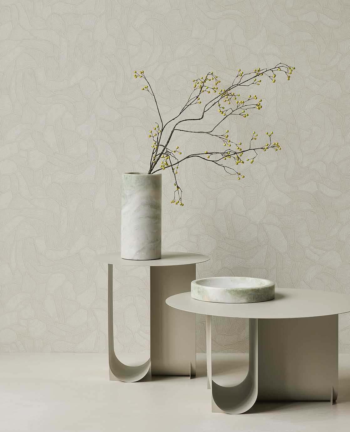 Pebble Relief wallpaper in light green behind white side tables with a vase of branches