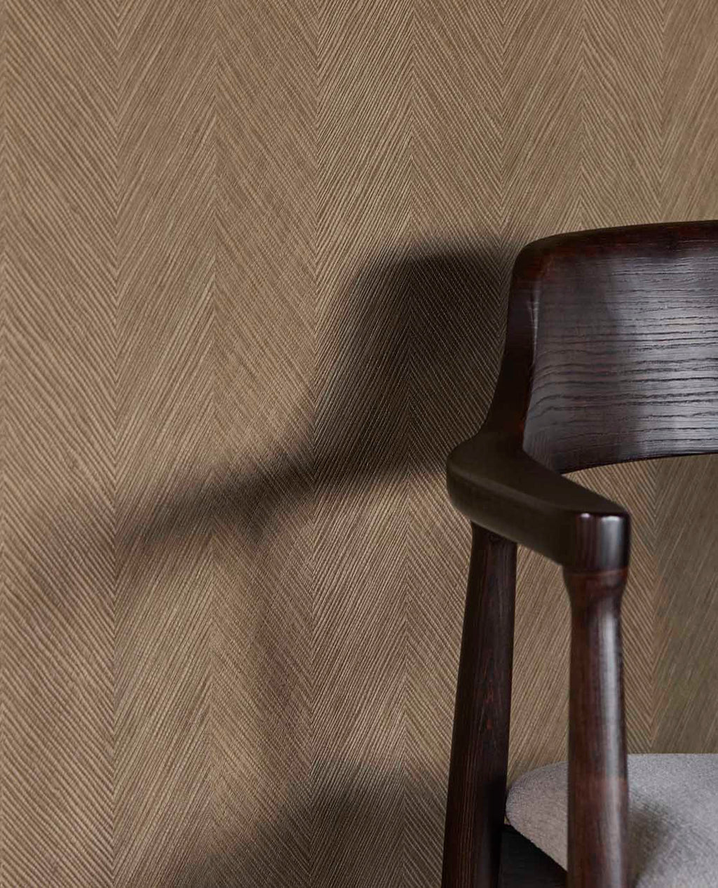 Woven Herringbone wallpaper in taupe beside a dark timber dining chair