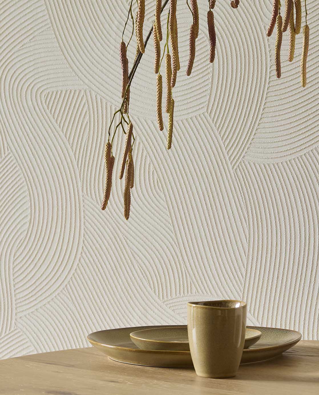 Raked Sand wallpaper in cream behind a timber table with ceramics and hanging branches
