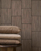 Woven Grid wallpaper in dark brown behind stacked cushions, close-up