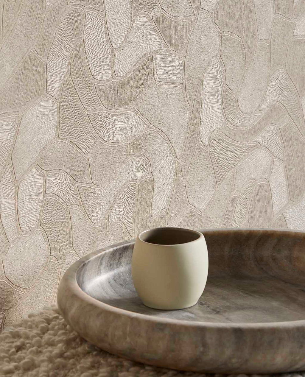 Pebble Relief wallpaper in beige, close-up behind a timber bowl