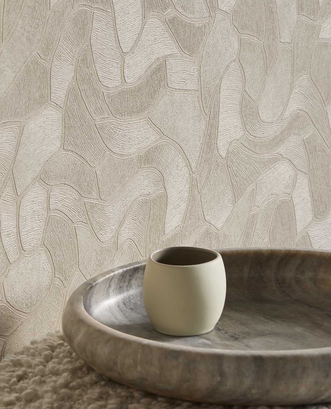 Pebble Relief wallpaper in beige, close-up behind a timber bowl