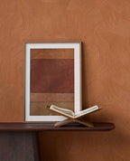 Raked Sand wallpaper in terracotta orange behind framed art on a dark console
