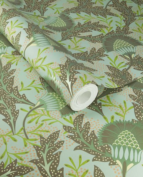 Banksia Bloom wallpaper by Eijffinger in sage green with brown leaves and coral dots, shown on a partially unrolled roll