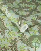 Banksia Bloom wallpaper by Eijffinger in sage green with brown leaves and coral dots, shown on a partially unrolled roll