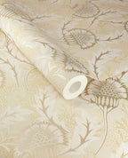 Banksia Bloom wallpaper by Eijffinger, cream and soft gold thistle floral motif shown on a partially unrolled swatch
