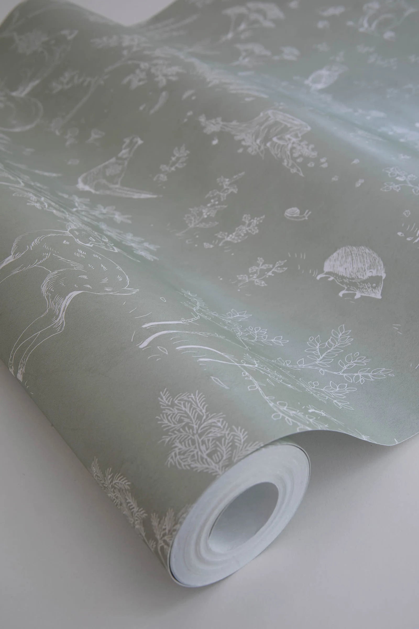 Hollie wallpaper by Sandberg, close-up of a sage green woodland-print roll showing fine deer and tree detail