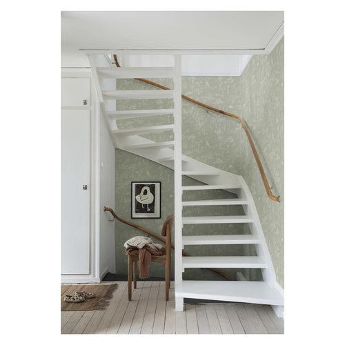 Hollie wallpaper by Sandberg in sage green woodland print behind a white spiral staircase in a hallway