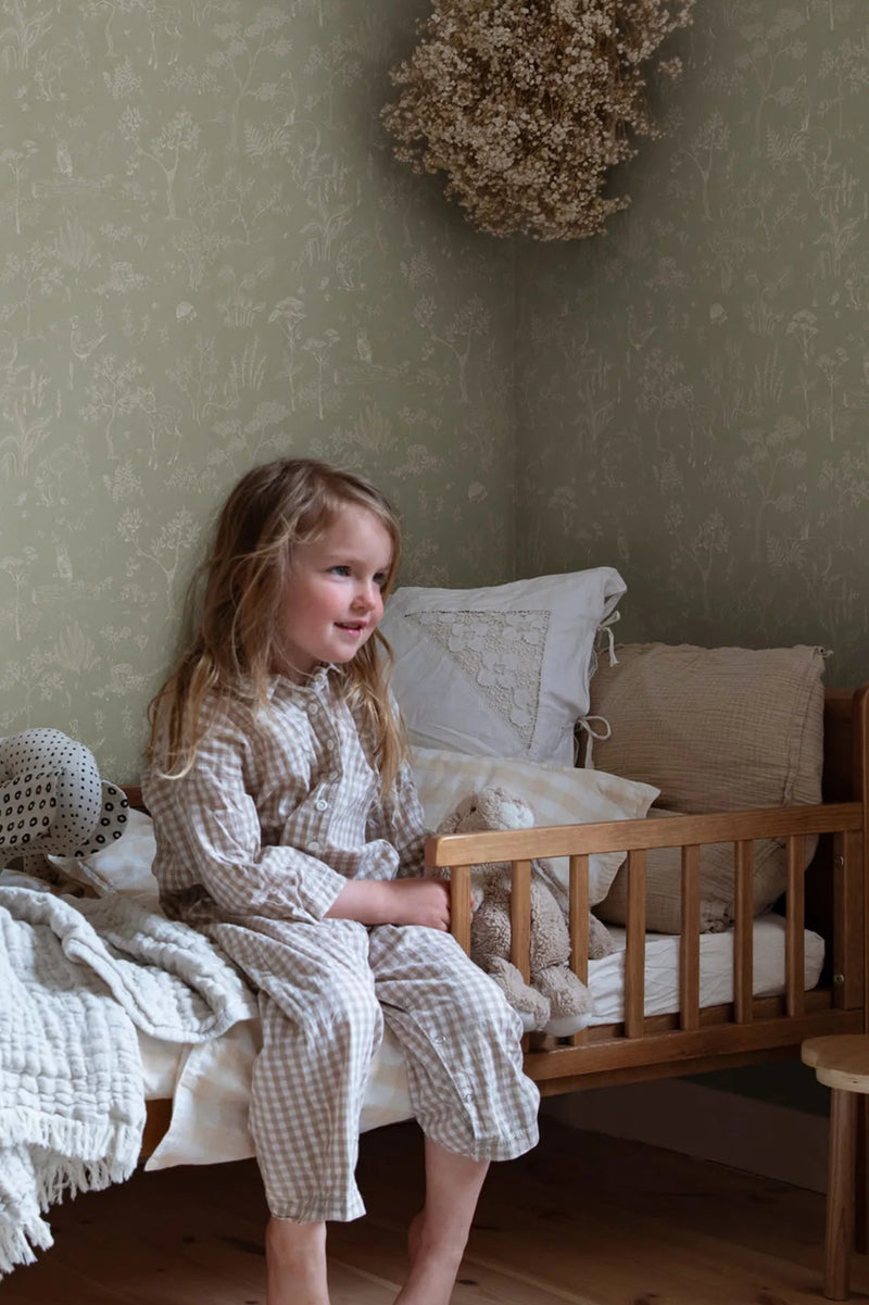 Hollie wallpaper by Sandberg in sage green woodland print in a cosy child bedroom corner with wooden cot bed
