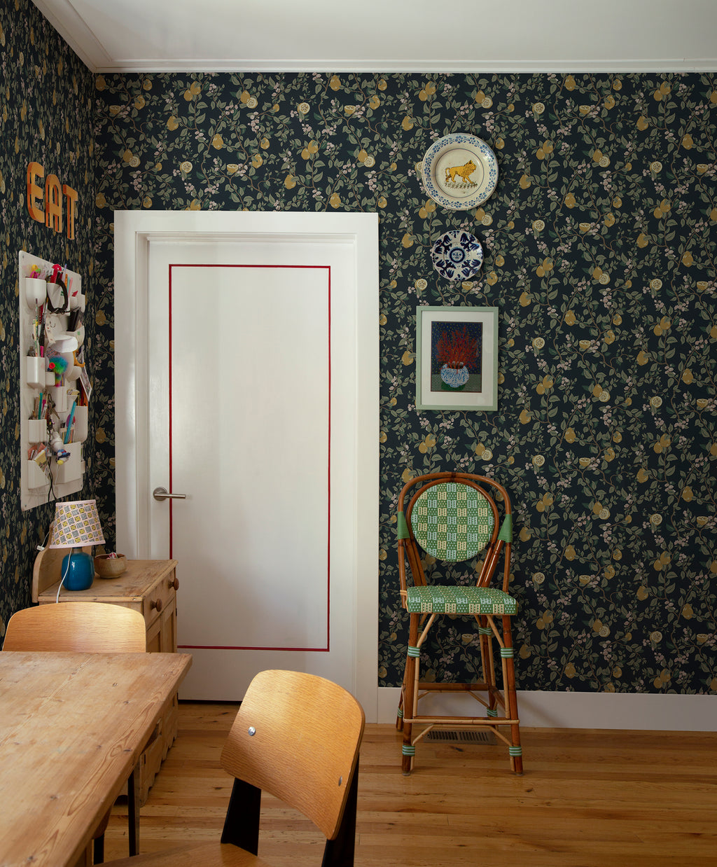 Kvitten wallpaper by Sandberg, navy quince design in a dining room with a white door and rattan bistro chair