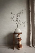 Raphael wallpaper by Sandberg in tonal white behind a branch arrangement on a stacked-stone plinth, styled corner