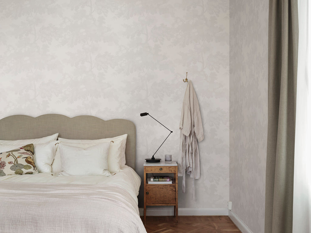 Raphael wallpaper by Sandberg in tonal white oak-tree print in a calm bedroom with a linen headboard and robe hook