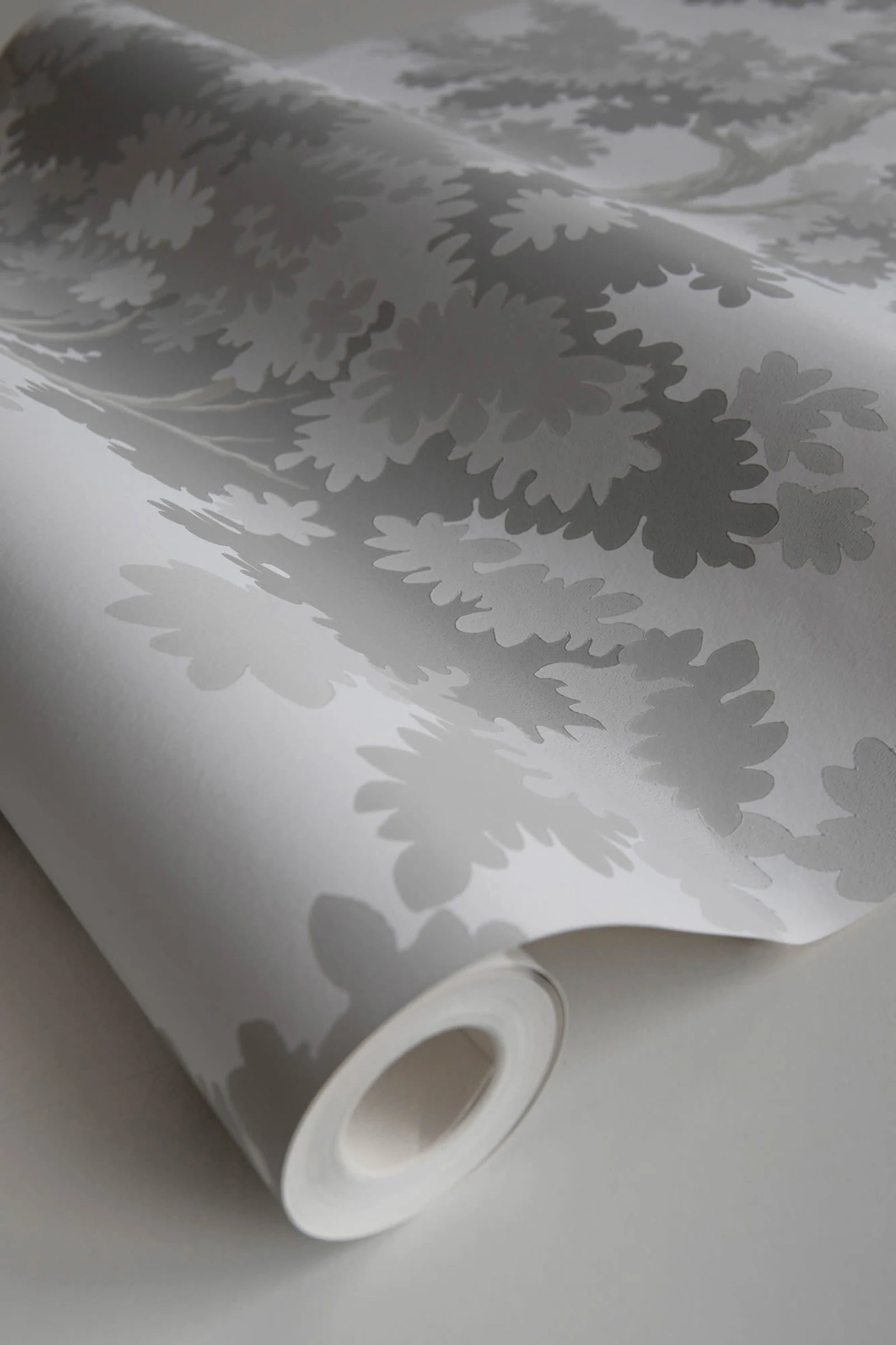 Raphael wallpaper by Sandberg, close-up of a part-rolled roll in soft grey oak-tree print