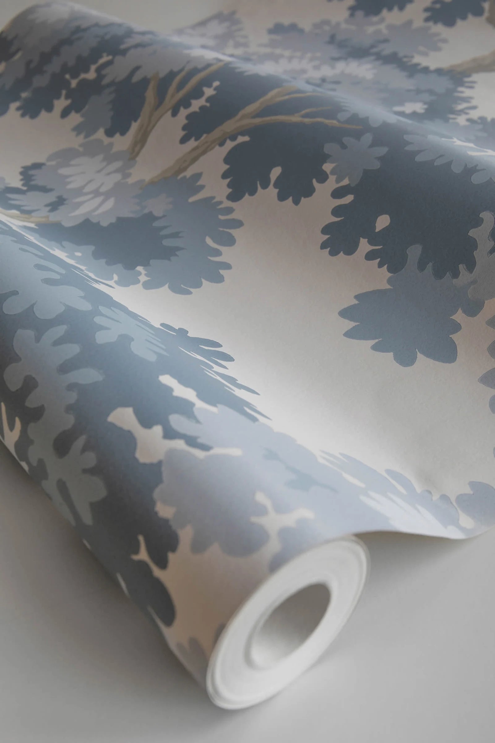 Raphael wallpaper by Sandberg, close-up of a part-rolled roll in blue oak-tree print on cream