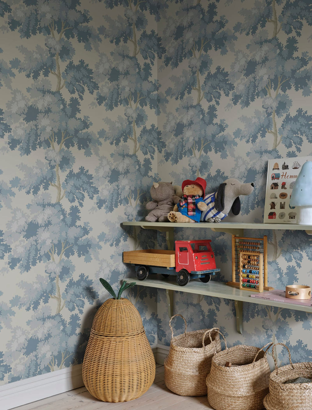 Raphael wallpaper by Sandberg in blue oak-tree print in a childrens room with shelves of toys and woven baskets