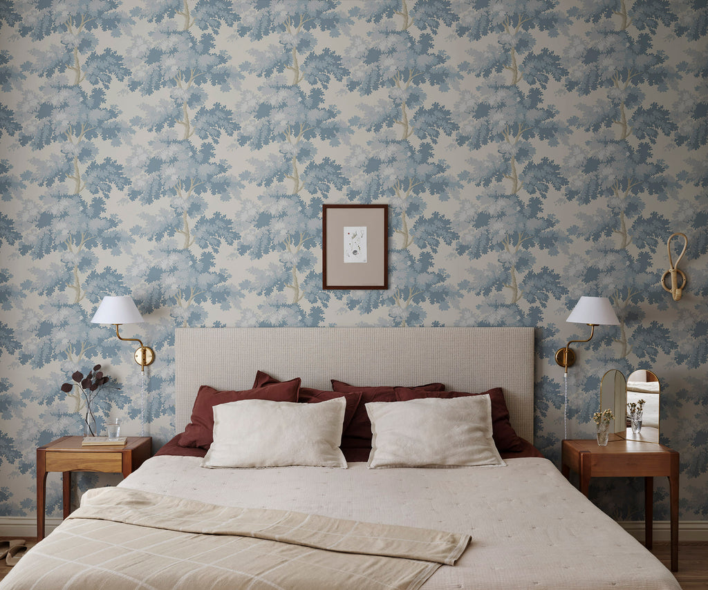 Raphael wallpaper by Sandberg in blue oak-tree print on cream behind a bed with red and ivory linens