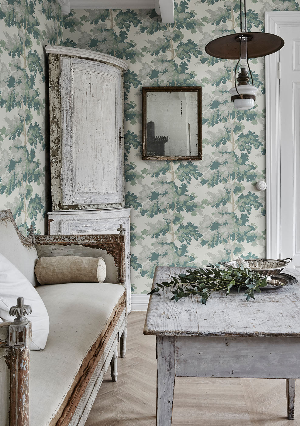 Raphael wallpaper by Sandberg in Green in a rustic room with a weathered timber table, antique mirror and pale linen sofa