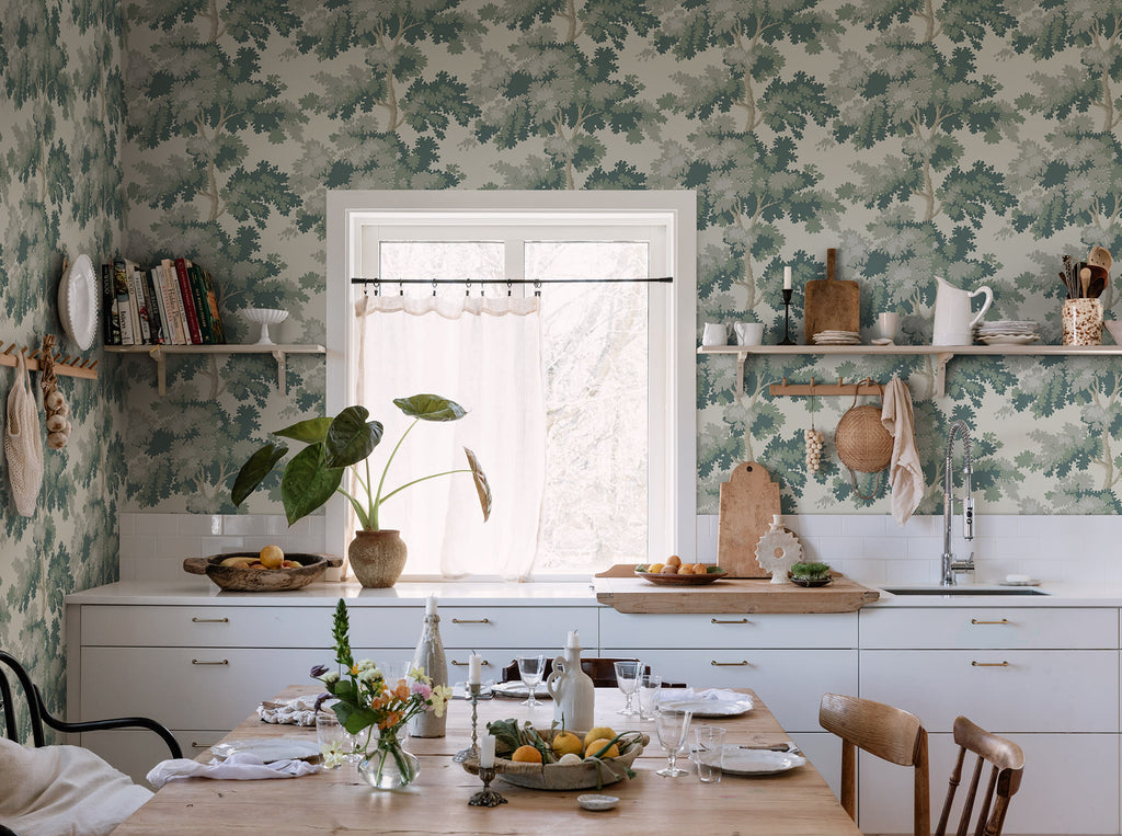 Raphael wallpaper by Sandberg in Green in a kitchen with open shelving, a timber dining table and a cafe curtain