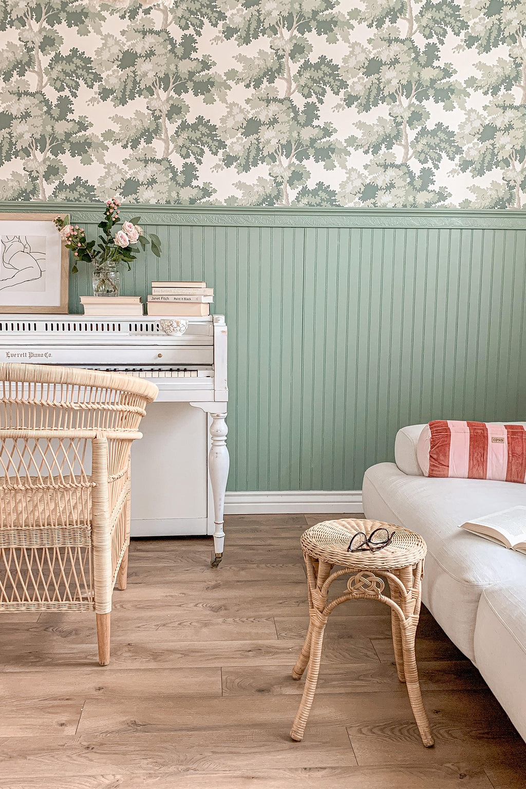 Raphael wallpaper by Sandberg in Green above sage beadboard panelling, with a white piano and wicker chair
