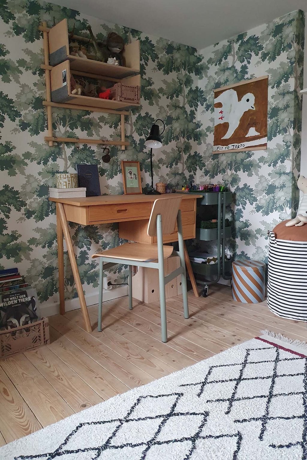 Raphael wallpaper by Sandberg in Green in a study corner with a timber desk, open shelving and a patterned rug