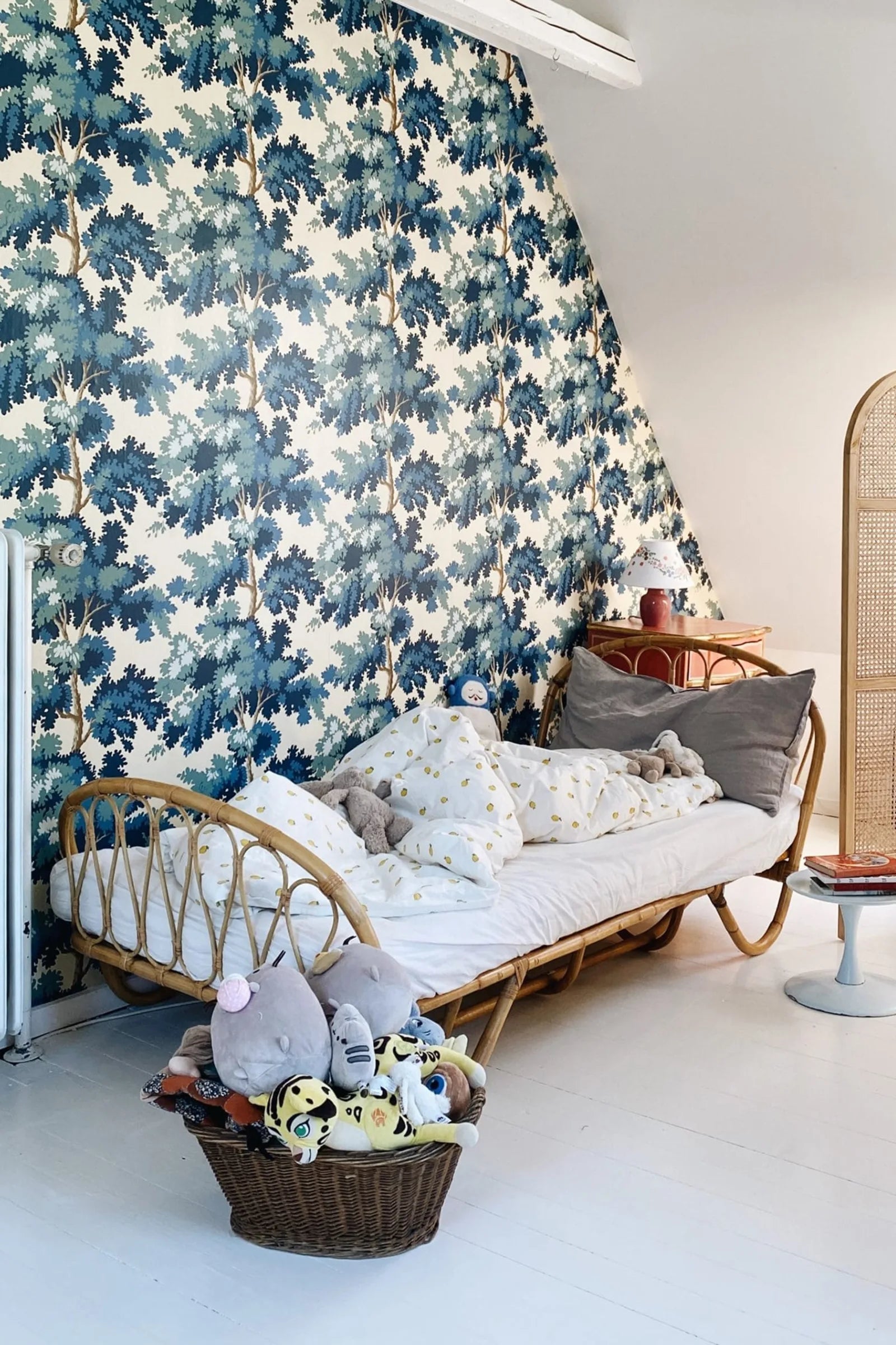 Raphael wallpaper by Sandberg in blue and green oak-tree print in a sloped-ceiling room with a rattan daybed