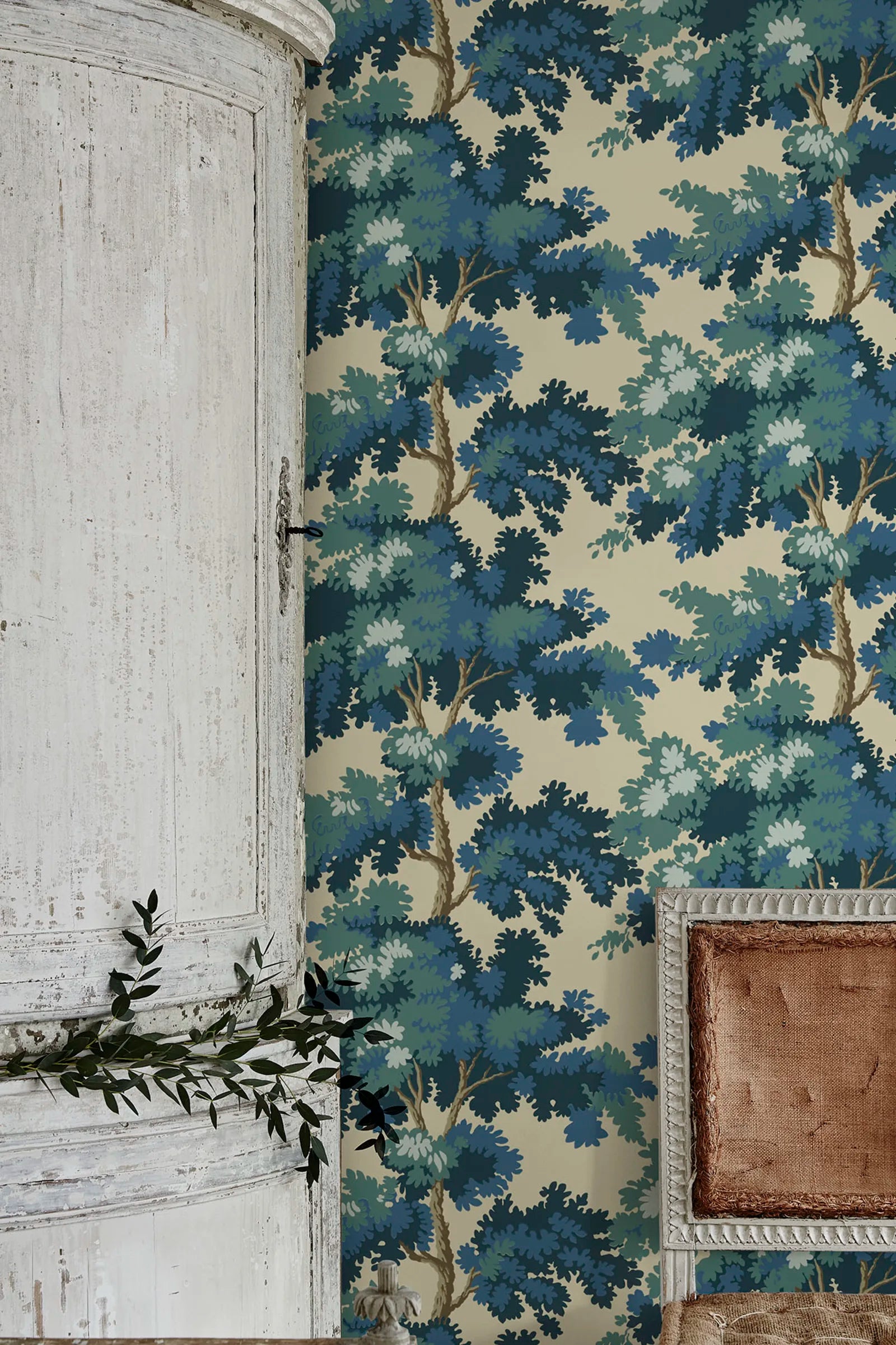 Raphael wallpaper by Sandberg in blue and green oak-tree print on cream beside a rustic distressed cabinet