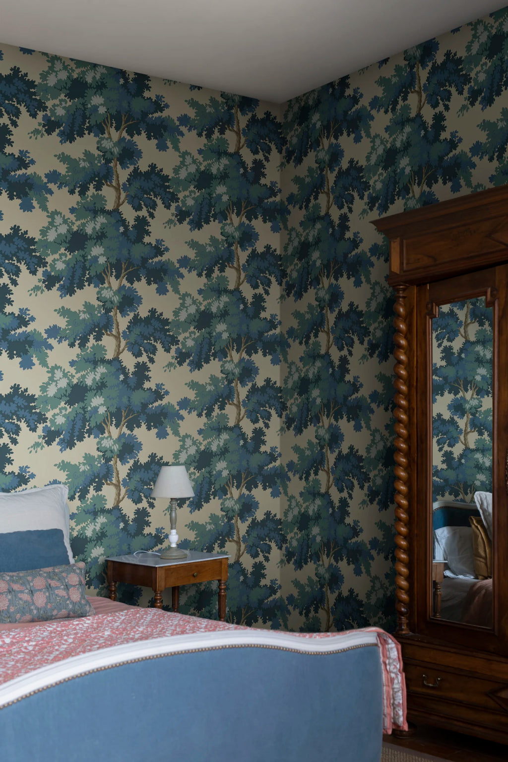 Raphael wallpaper by Sandberg in blue and green oak-tree print on yellow behind a wooden bed and mirrored armoire