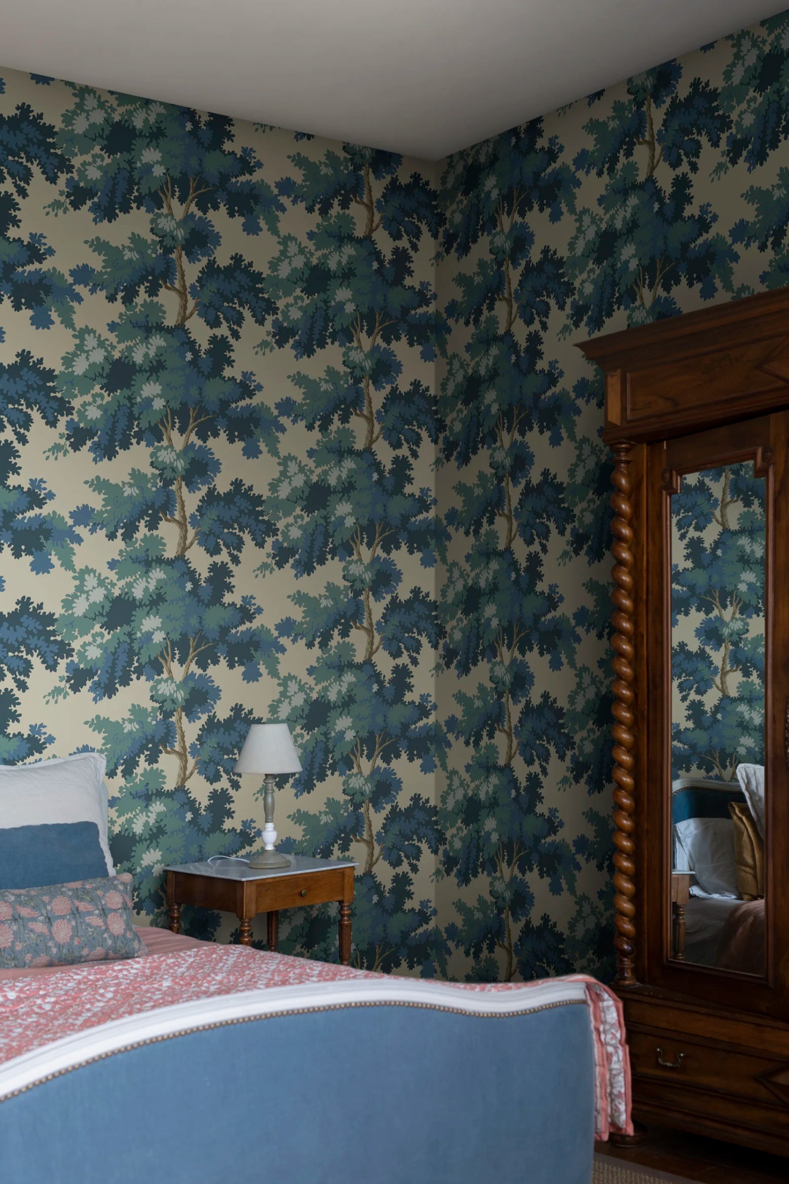 Raphael wallpaper by Sandberg in blue and green oak-tree print on yellow behind a wooden bed and mirrored armoire