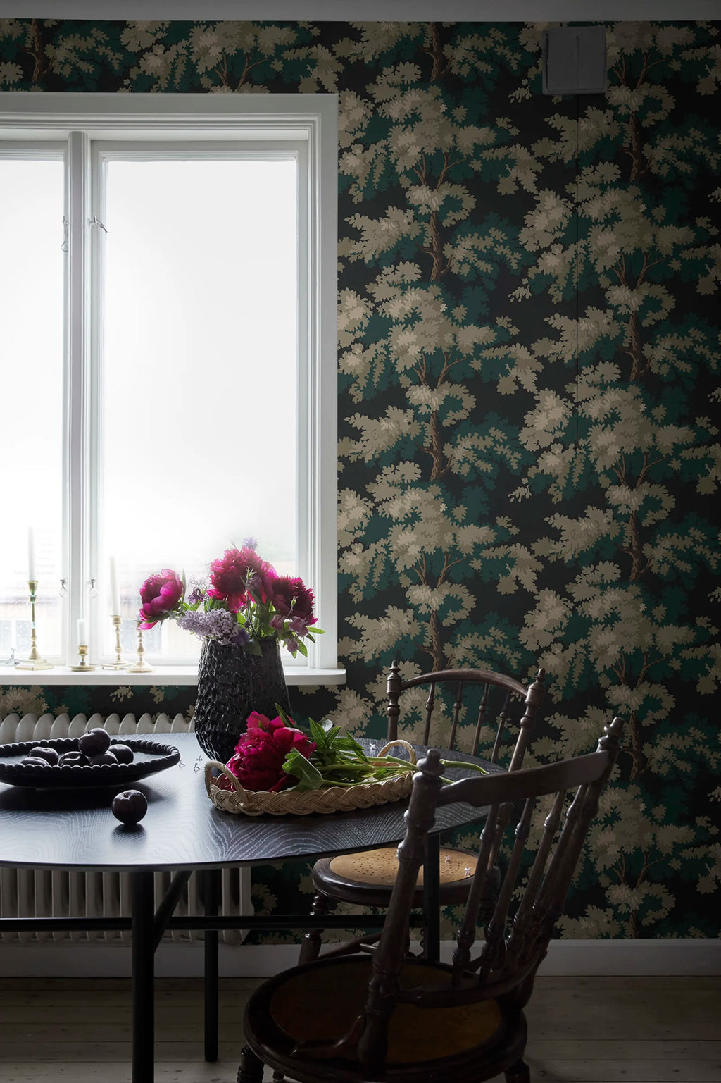 Raphael wallpaper by Sandberg in dark green oak-tree print in a dining nook with a black table and bright peonies
