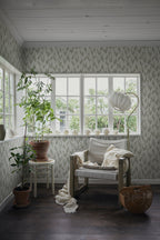 Liljekonvalj wallpaper by Sandberg, lily-of-the-valley print in a bright sunroom with a linen chair and potted plants