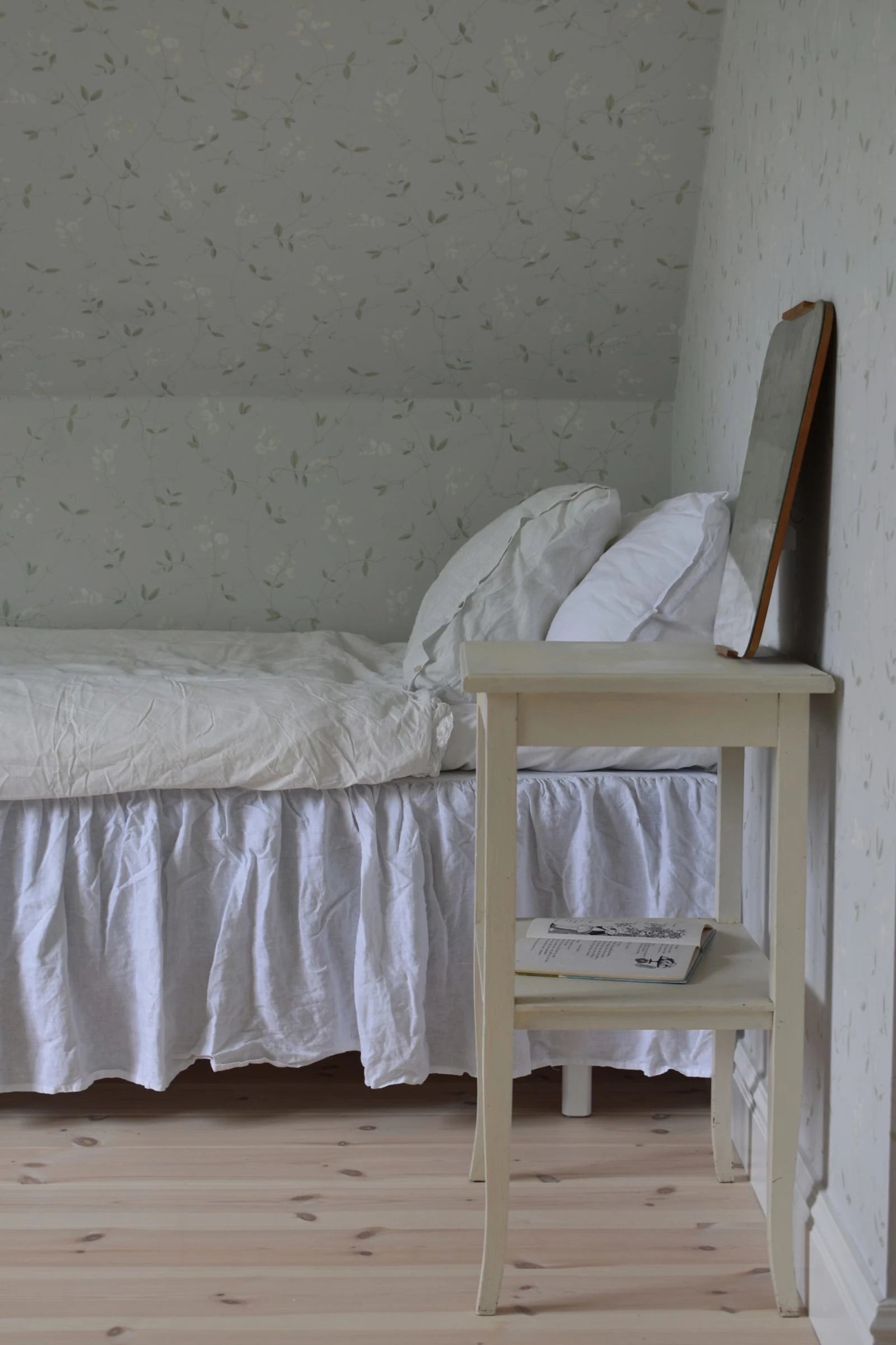 Sanna Sweet Pea wallpaper by Sandberg in pale sweet pea print in a sloped-ceiling bedroom with white bedding