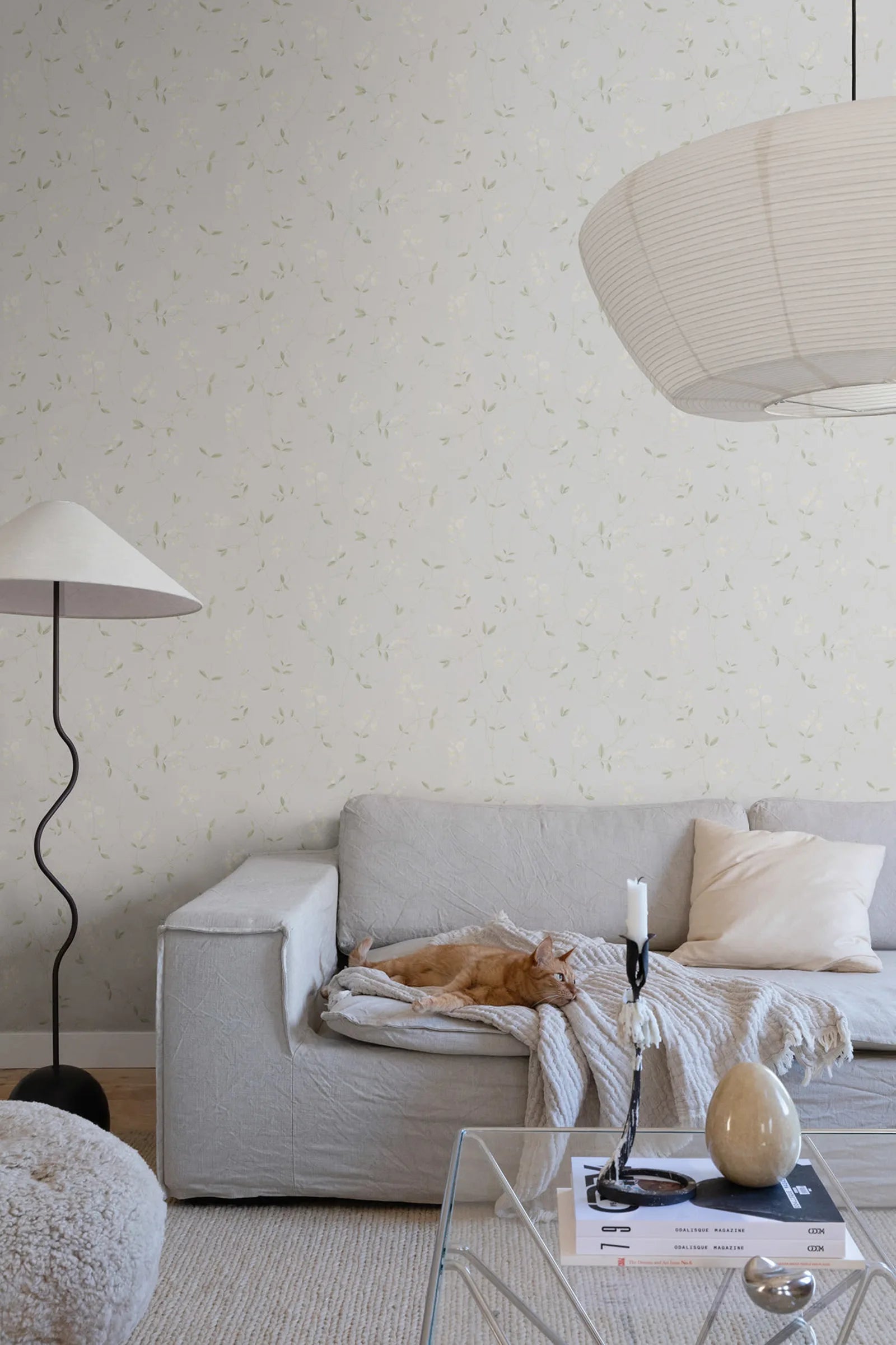 Sanna Sweet Pea wallpaper by Sandberg in soft cream sweet pea print in a living room with a linen sofa and ginger cat