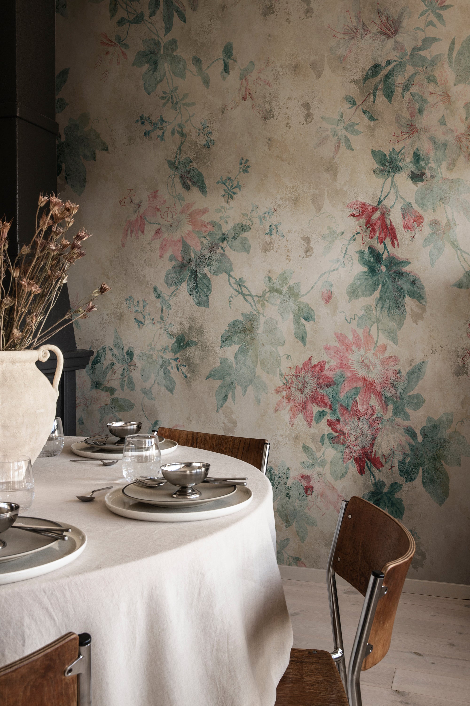 Faded Passion wall mural by Sandberg in weathered beige with pink passionflowers behind a linen dining table
